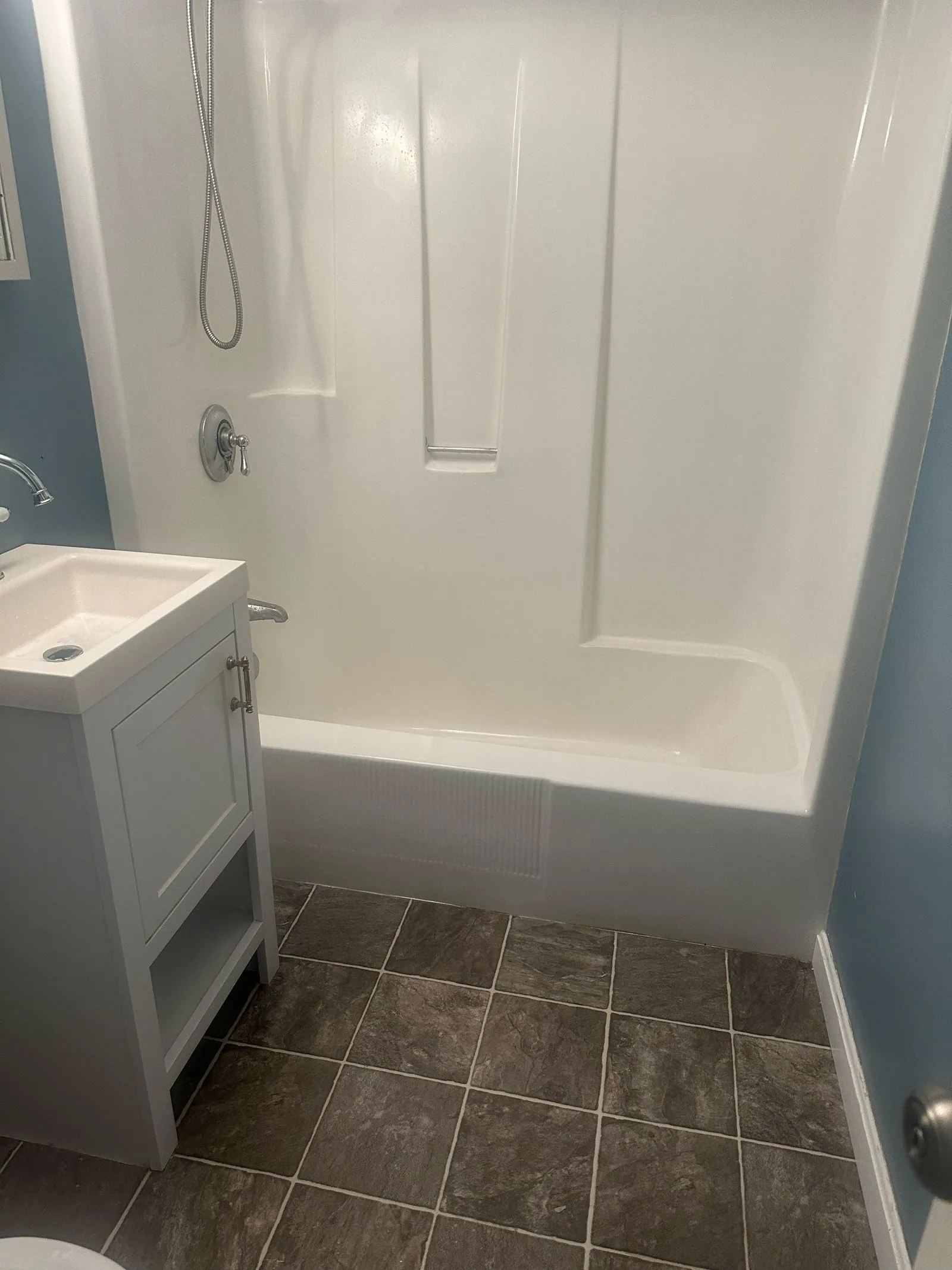 Clean white bathtub and vanity in a refreshed bathroom